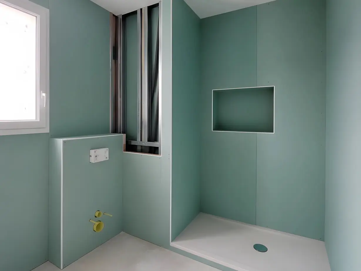Salle de bains habillée de plaques de plâtre hydrofugées vertes, avec une niche dans la douche et le bâti du WC coffré